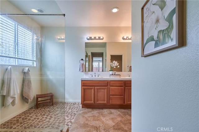 bathroom with double vanity, baseboards, a shower, and a sink