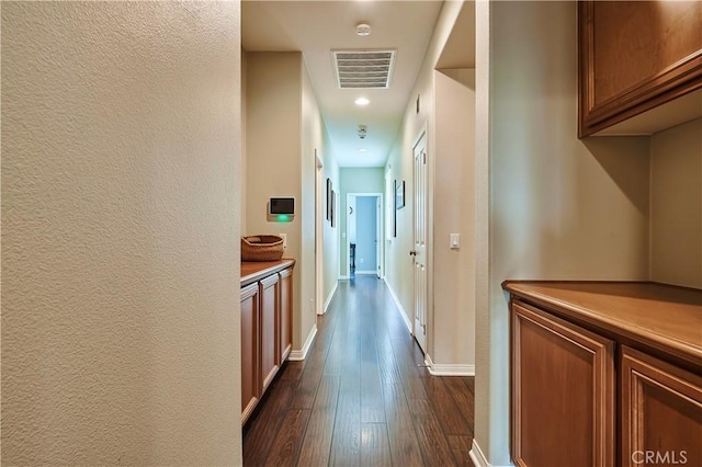 corridor featuring dark wood-style floors, visible vents, and baseboards