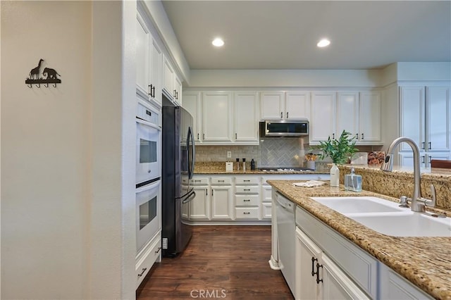 kitchen featuring a sink, white cabinetry, appliances with stainless steel finishes, decorative backsplash, and dark wood-style floors