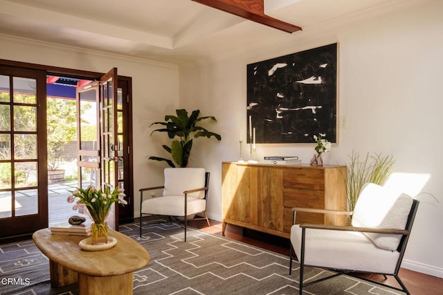 sitting room with ornamental molding, a raised ceiling, baseboards, and wood finished floors