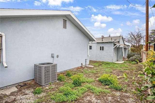 rear view of property featuring stucco siding and central air condition unit