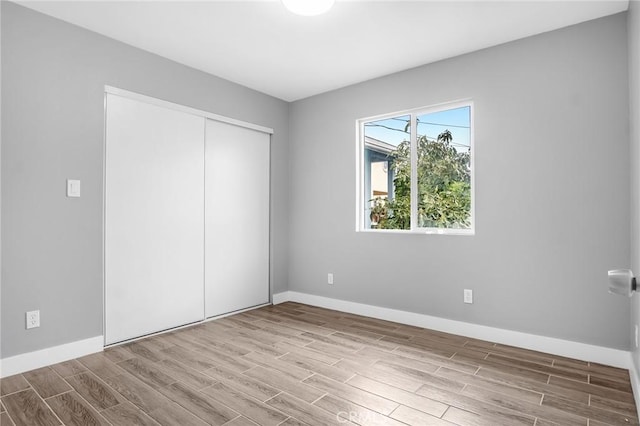 unfurnished bedroom with wood finish floors, a closet, and baseboards