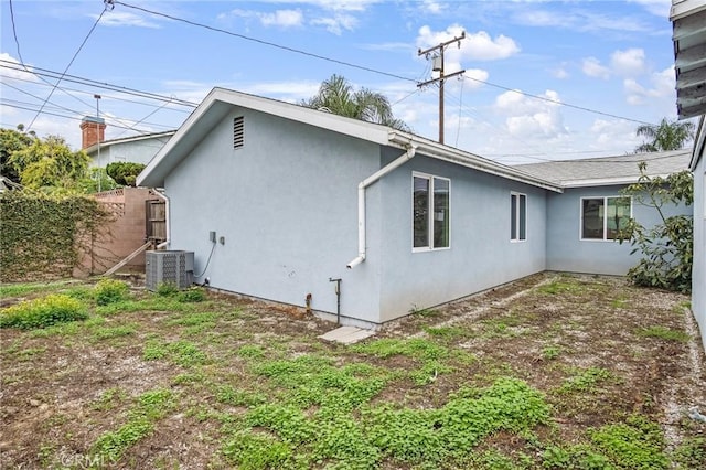 back of property featuring stucco siding, fence, and central air condition unit