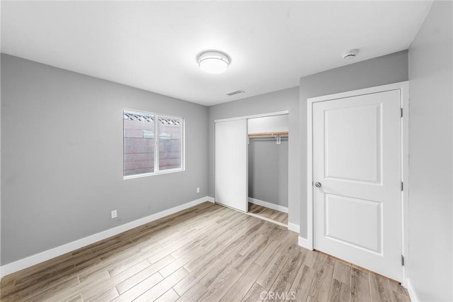 unfurnished bedroom featuring light wood-style flooring, visible vents, baseboards, and a closet