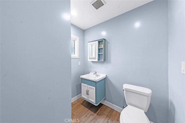 bathroom featuring baseboards, visible vents, toilet, wood finished floors, and vanity