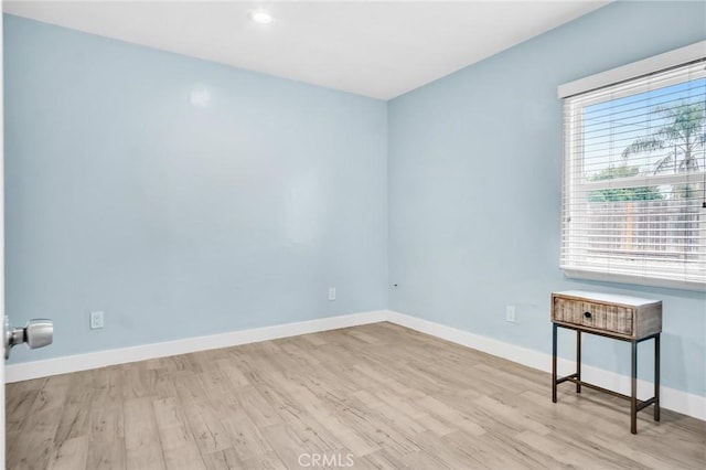 spare room featuring baseboards and wood finished floors