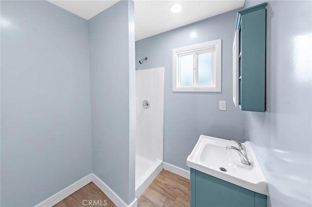 full bathroom with a stall shower, baseboards, and wood finished floors