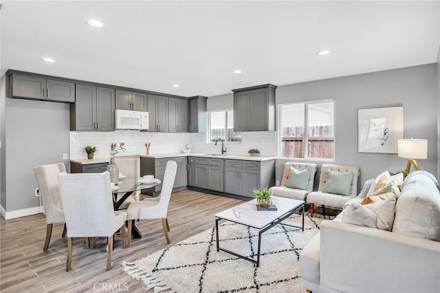 living room featuring baseboards, recessed lighting, and light wood-style floors