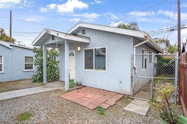 view of front of property featuring a gate, fence, and stucco siding