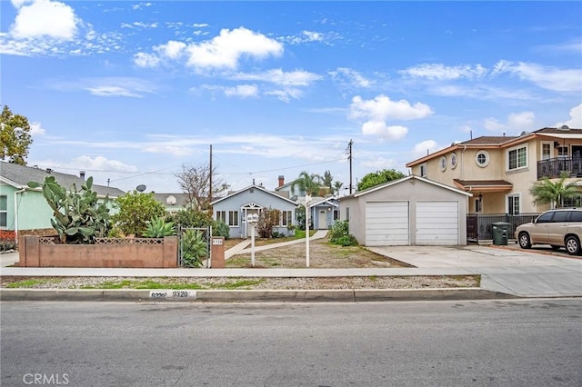 view of front of home featuring a garage, concrete driveway, fence, and a residential view