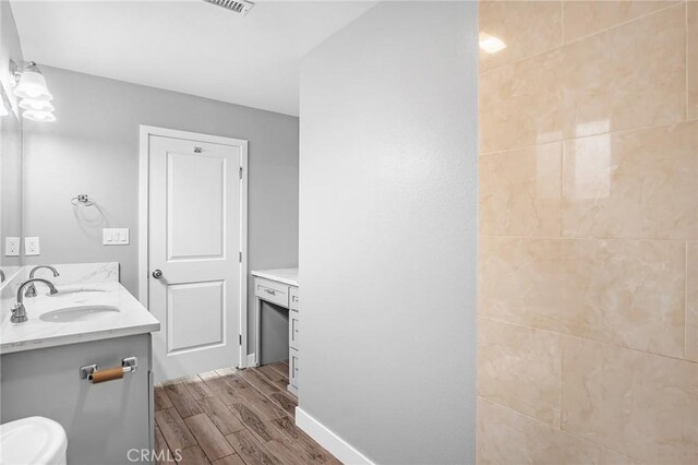 full bath featuring wood tiled floor, vanity, and baseboards