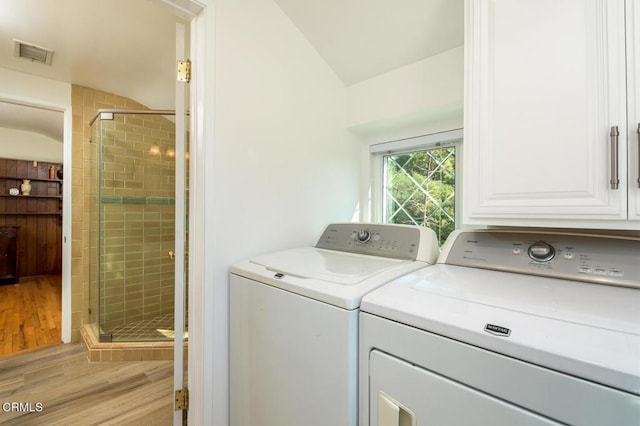 washroom featuring visible vents, separate washer and dryer, light wood-type flooring, and cabinet space