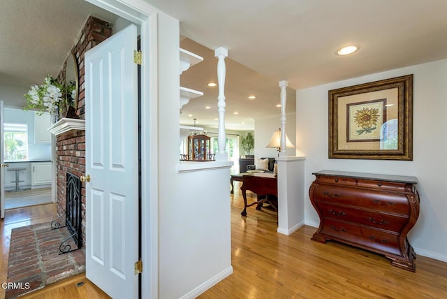 hallway featuring baseboards, light wood finished floors, and recessed lighting