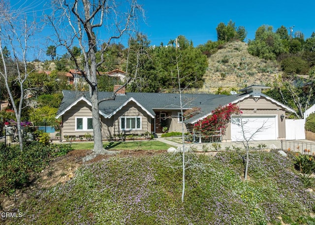 ranch-style house with a garage, a chimney, fence, and driveway