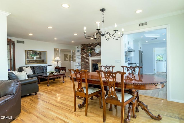 dining space with ornamental molding, light wood-style flooring, and visible vents