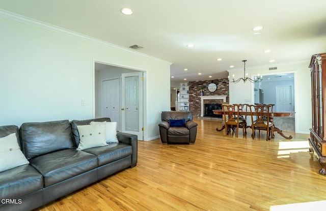 living room with a fireplace, recessed lighting, visible vents, light wood-style flooring, and ornamental molding