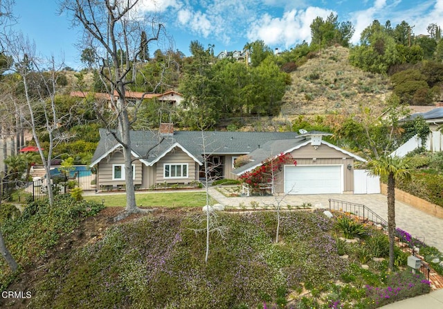 view of front of home featuring decorative driveway, fence, and an attached garage