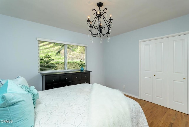 bedroom featuring a closet, a notable chandelier, baseboards, and wood finished floors