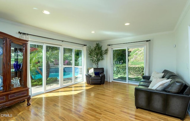 sitting room with ornamental molding, light wood finished floors, and recessed lighting