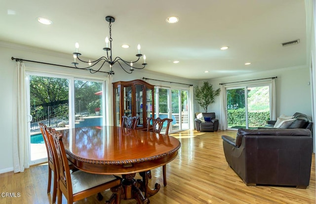 dining space with crown molding, a chandelier, plenty of natural light, and light wood-style flooring