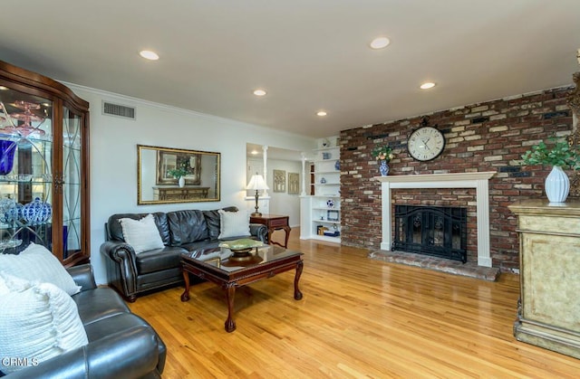 living room with visible vents, ornamental molding, wood finished floors, a fireplace, and recessed lighting