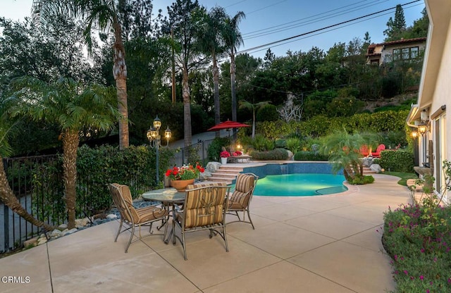 outdoor pool with outdoor dining area, a patio, and fence