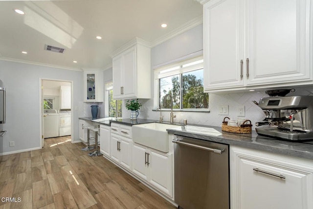 kitchen featuring visible vents, ornamental molding, washer and dryer, stainless steel dishwasher, and a sink