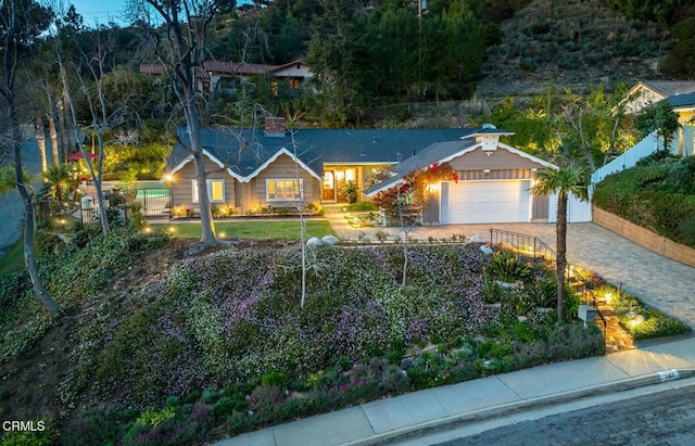 ranch-style home featuring a garage, decorative driveway, and fence