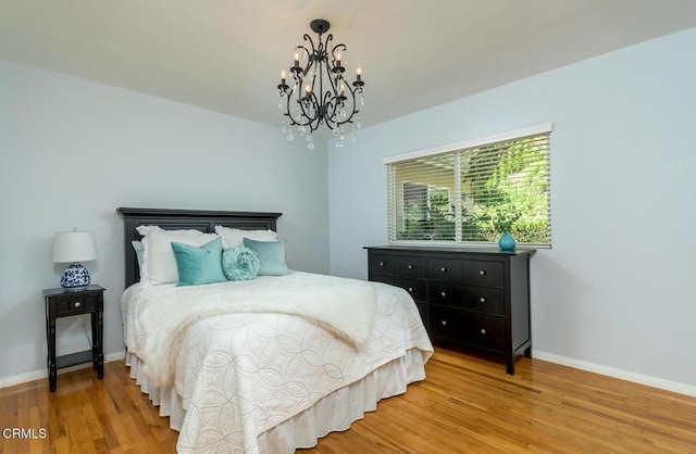 bedroom featuring a chandelier, wood finished floors, and baseboards