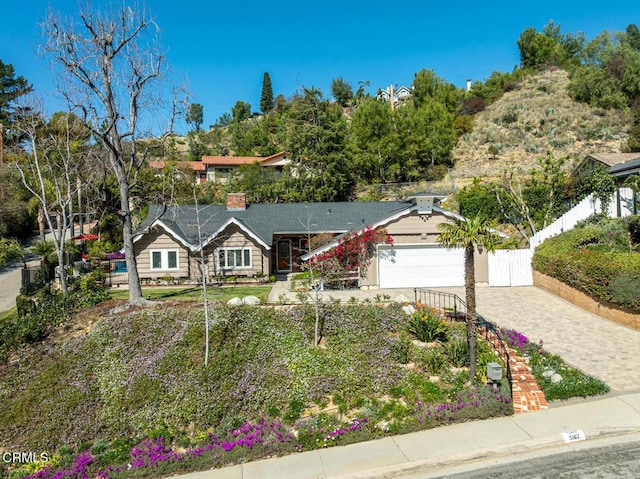 single story home featuring a garage, decorative driveway, fence, and a chimney