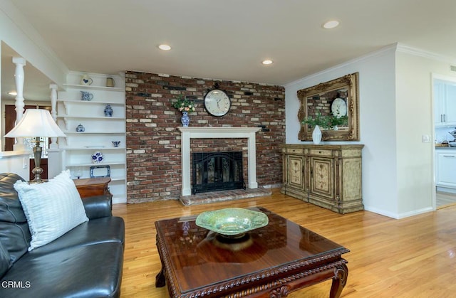 living area featuring baseboards, light wood-style flooring, crown molding, a brick fireplace, and recessed lighting