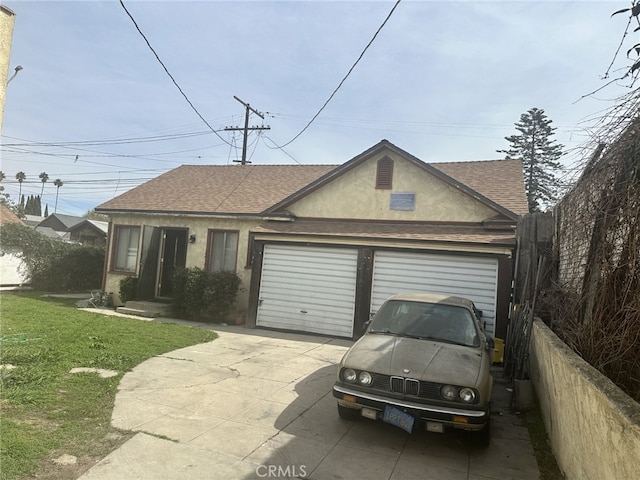 single story home featuring a shingled roof, concrete driveway, a garage, and stucco siding