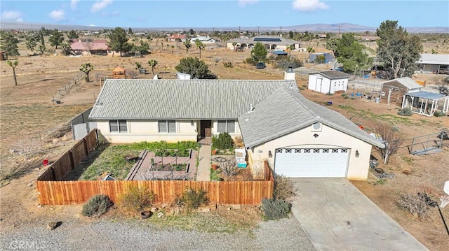 view of front of home with concrete driveway, a fenced front yard, a mountain view, and stucco siding