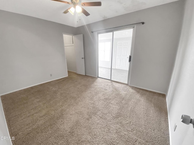 carpeted spare room featuring a ceiling fan and baseboards