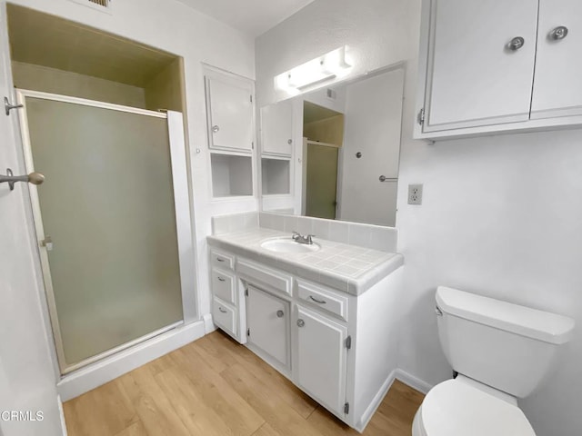 full bathroom featuring toilet, a stall shower, wood finished floors, and vanity