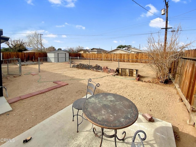 view of yard with a patio, outdoor dining area, a fenced backyard, an outdoor structure, and a storage unit