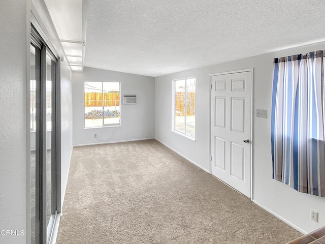 unfurnished room featuring carpet floors, a textured ceiling, baseboards, and an AC wall unit