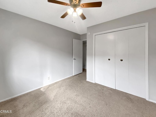 unfurnished bedroom with carpet floors, a ceiling fan, baseboards, and a closet