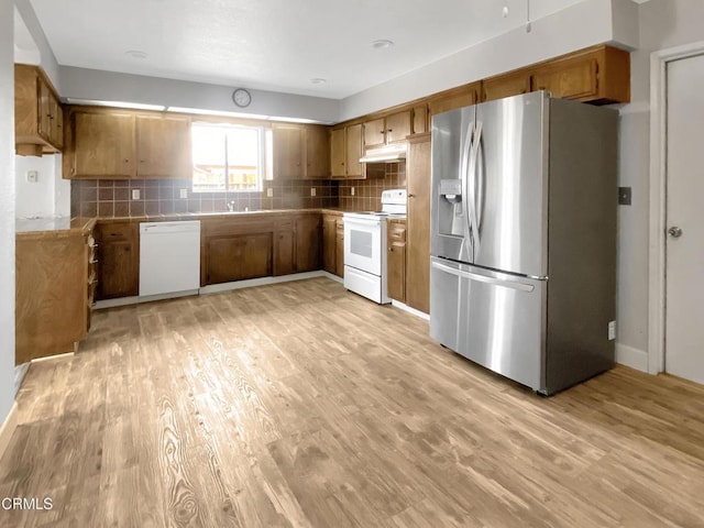 kitchen featuring light wood-type flooring, white appliances, brown cabinets, and decorative backsplash