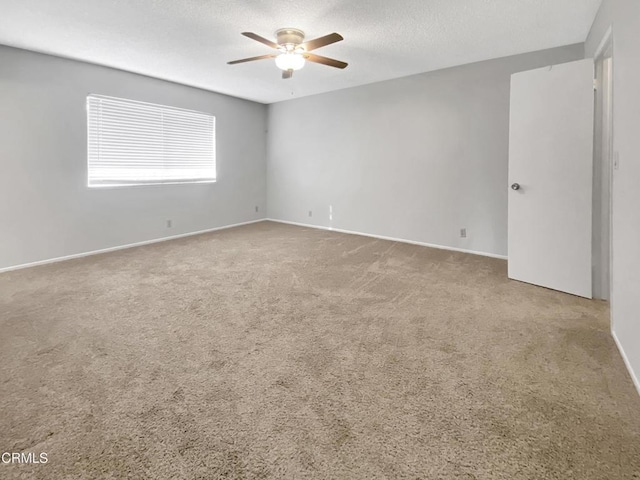 carpeted spare room featuring ceiling fan, baseboards, and a textured ceiling