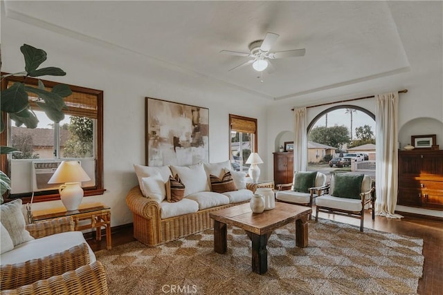 sitting room featuring a raised ceiling, plenty of natural light, wood finished floors, and ceiling fan