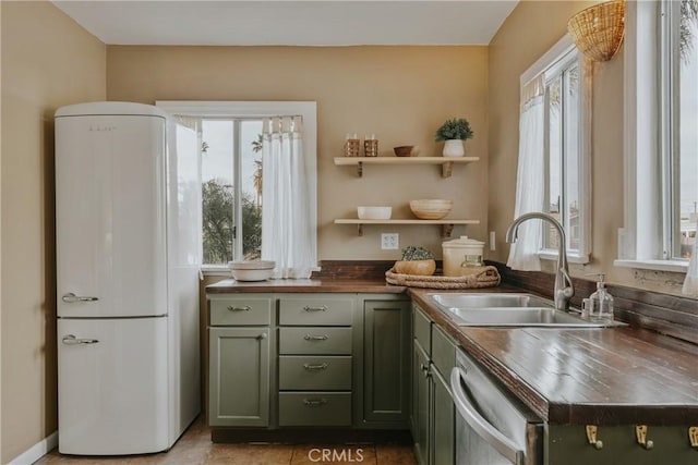 kitchen with green cabinets, dishwasher, freestanding refrigerator, and butcher block counters