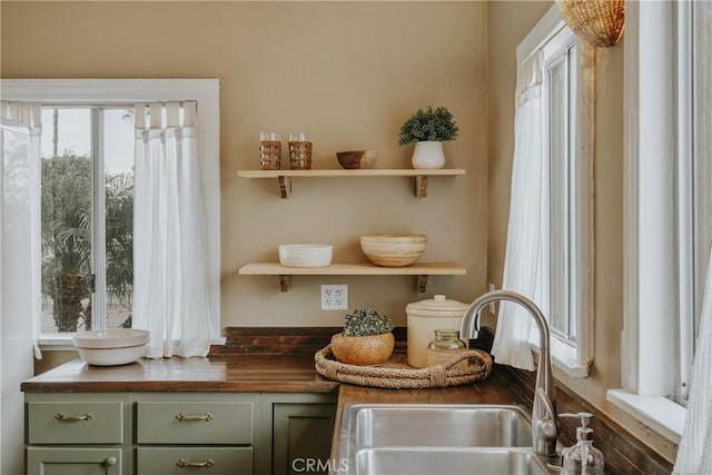 interior details with green cabinetry, wood counters, open shelves, and a sink