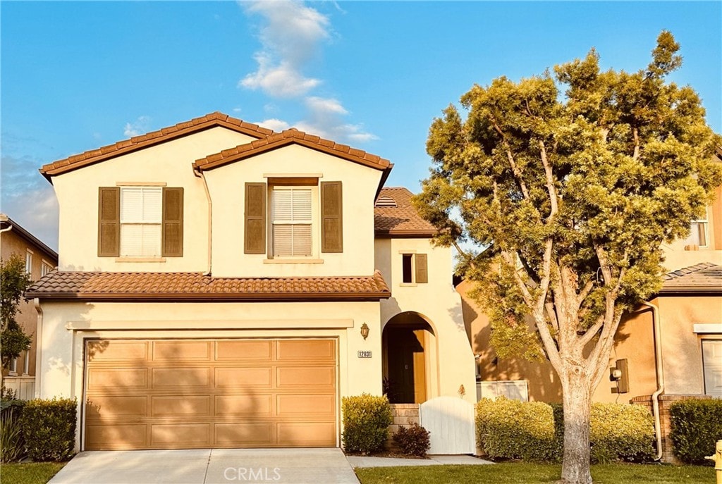 mediterranean / spanish house with stucco siding, an attached garage, and driveway