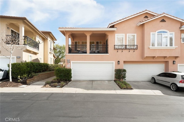 view of front of house featuring concrete driveway, an attached garage, a tile roof, and stucco siding