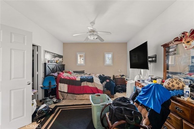 carpeted bedroom featuring an accent wall, ceiling fan, and wallpapered walls