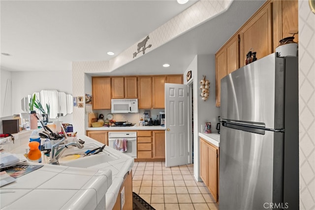 kitchen with light tile patterned floors, tile counters, recessed lighting, a sink, and white appliances