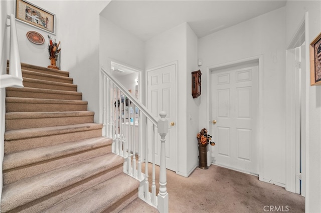 carpeted entrance foyer with stairs