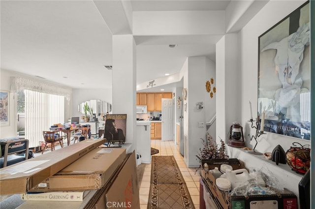 interior space with light brown cabinetry, white microwave, and light tile patterned floors