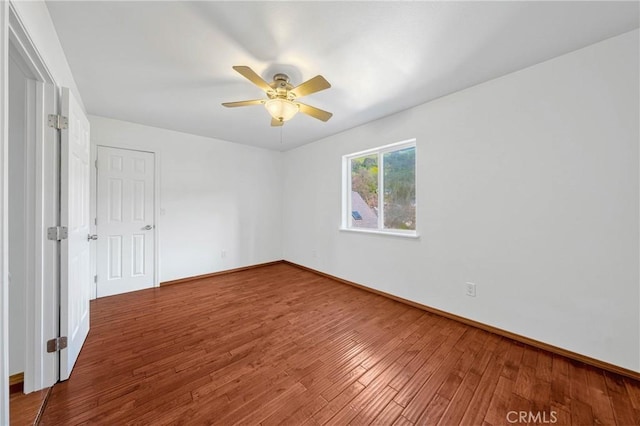 empty room featuring ceiling fan, baseboards, and wood finished floors